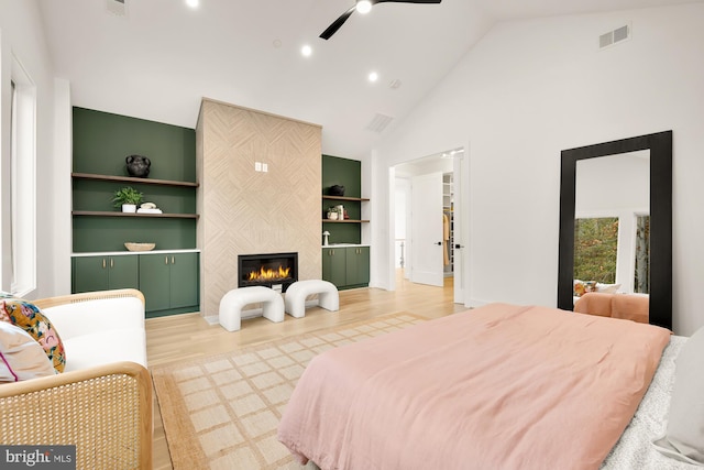 bedroom featuring a fireplace, high vaulted ceiling, ceiling fan, and hardwood / wood-style floors