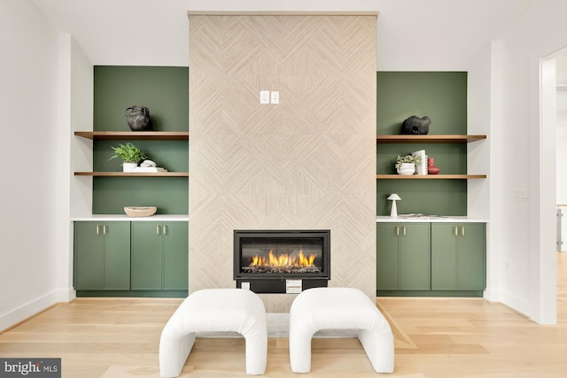 sitting room with a fireplace, light wood-type flooring, and built in features