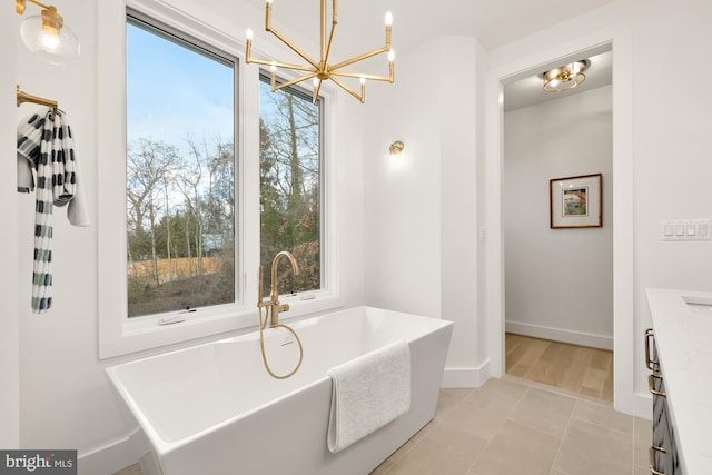 bathroom with a notable chandelier, a bathtub, tile patterned flooring, and vanity