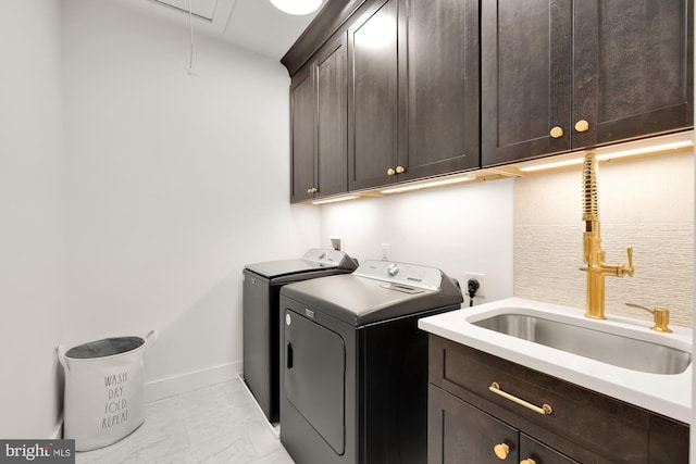 laundry area with sink, washing machine and clothes dryer, and cabinets