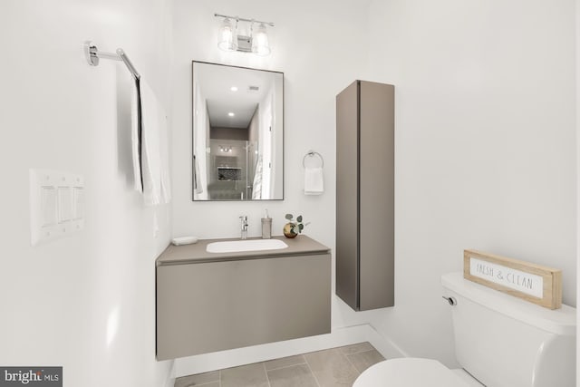 bathroom with toilet, vanity, and tile patterned flooring