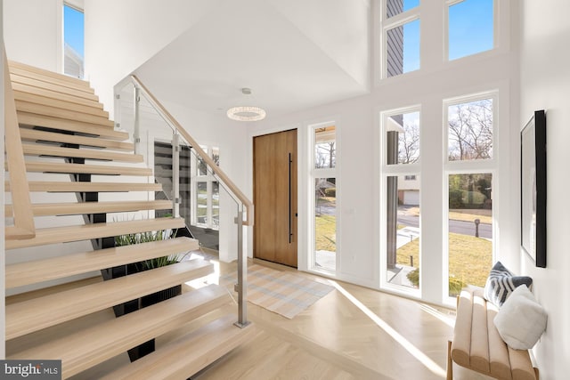 interior space with a high ceiling, a chandelier, parquet floors, and a healthy amount of sunlight