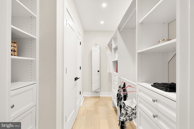 walk in closet with light hardwood / wood-style flooring