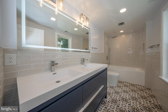 full bathroom featuring tile patterned flooring, toilet, tiled shower / bath, and tile walls