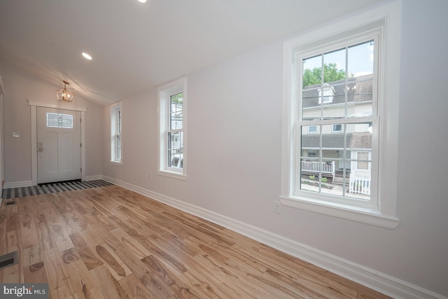 foyer featuring an inviting chandelier, light hardwood / wood-style flooring, and vaulted ceiling