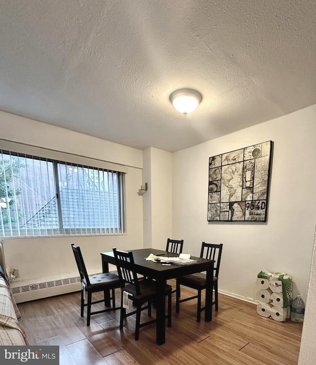 dining room with wood-type flooring, a textured ceiling, and baseboard heating