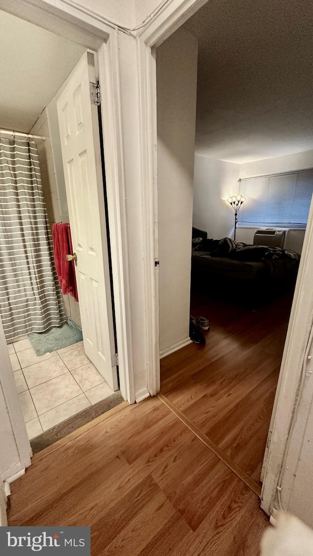 hallway with light wood-type flooring and a textured ceiling