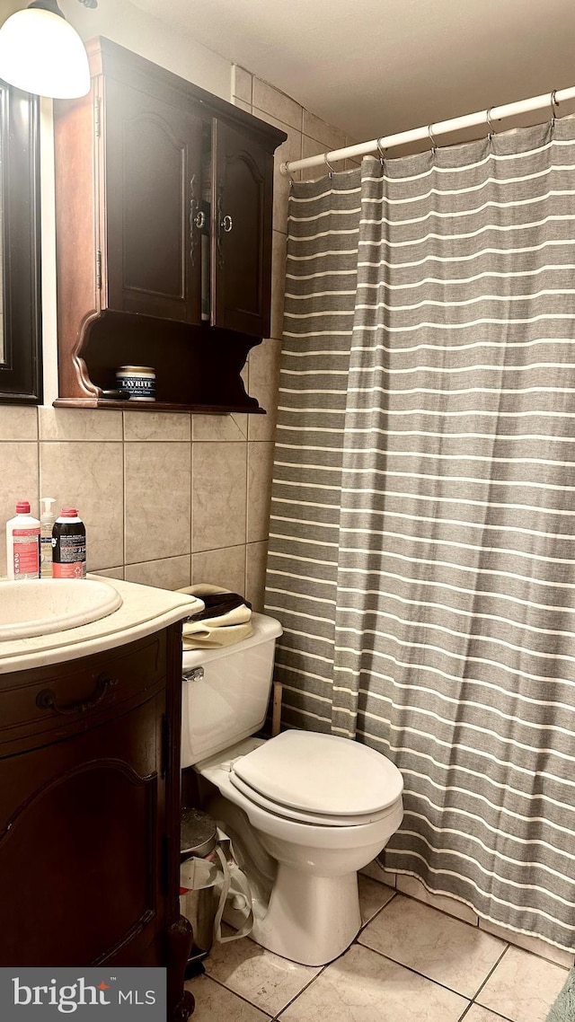 bathroom featuring tile patterned flooring, vanity, toilet, and tile walls