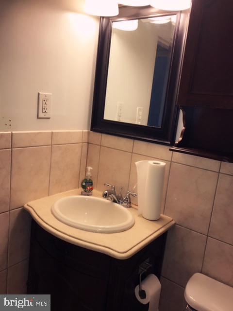 bathroom featuring vanity, toilet, and tile walls