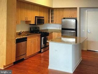 kitchen with appliances with stainless steel finishes, a center island, dark hardwood / wood-style flooring, and sink