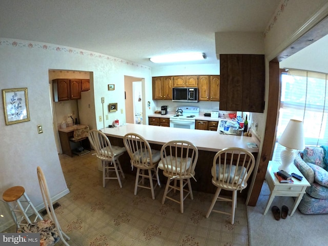 kitchen with electric stove, a breakfast bar, and kitchen peninsula