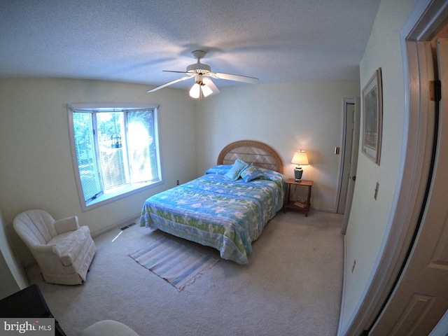 bedroom with a textured ceiling, ceiling fan, and light carpet