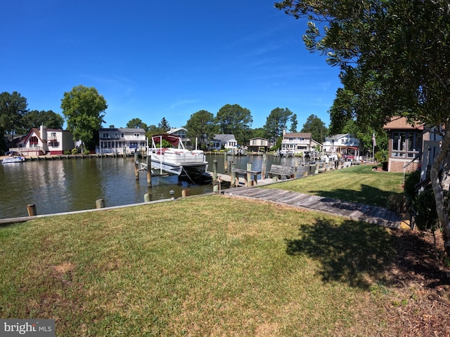 view of dock with a lawn and a water view