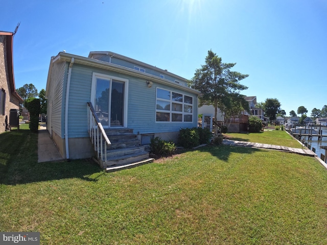 back of property featuring a water view and a lawn