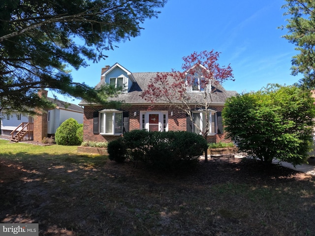 cape cod home featuring a front yard