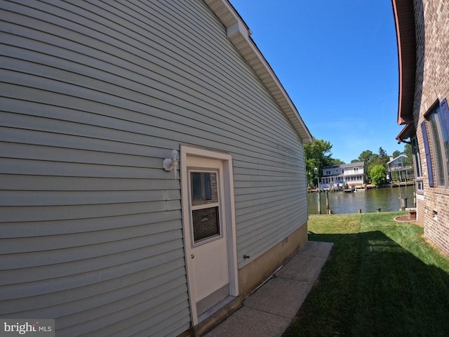 view of side of home with a yard and a water view