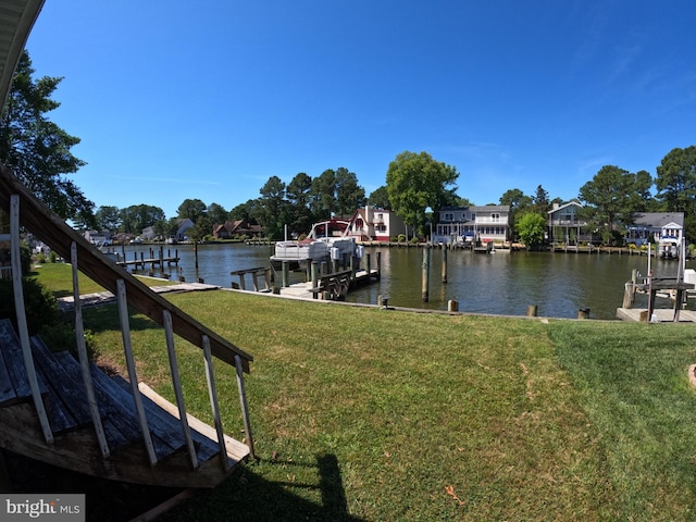 view of dock with a lawn and a water view