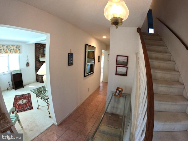 staircase with a fireplace and tile patterned floors