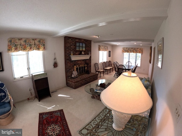 carpeted living room with beamed ceiling, a wealth of natural light, and a fireplace