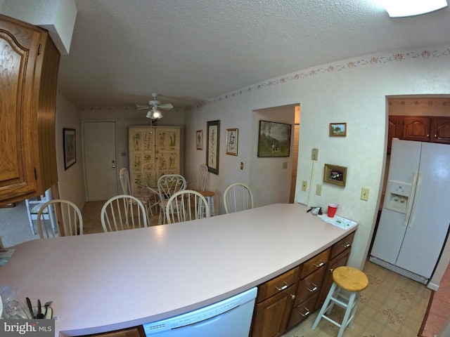 kitchen featuring white appliances, a textured ceiling, and ceiling fan