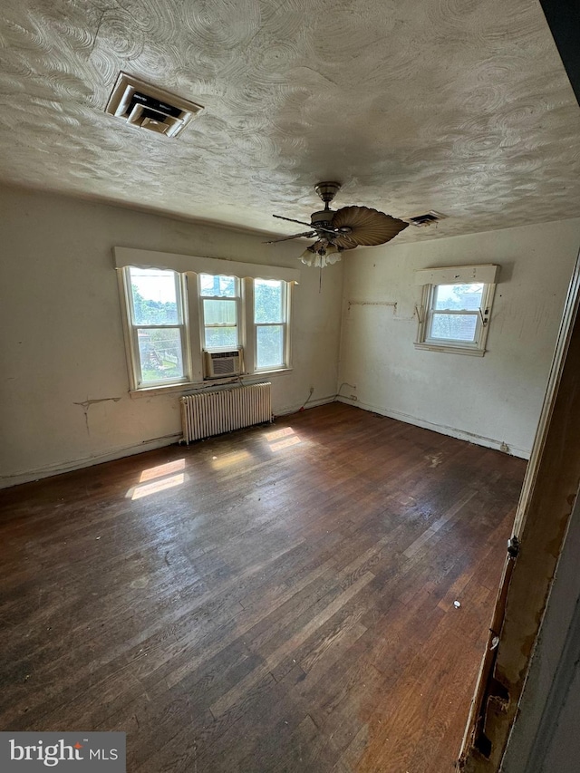 spare room with ceiling fan, cooling unit, radiator heating unit, and dark wood-type flooring