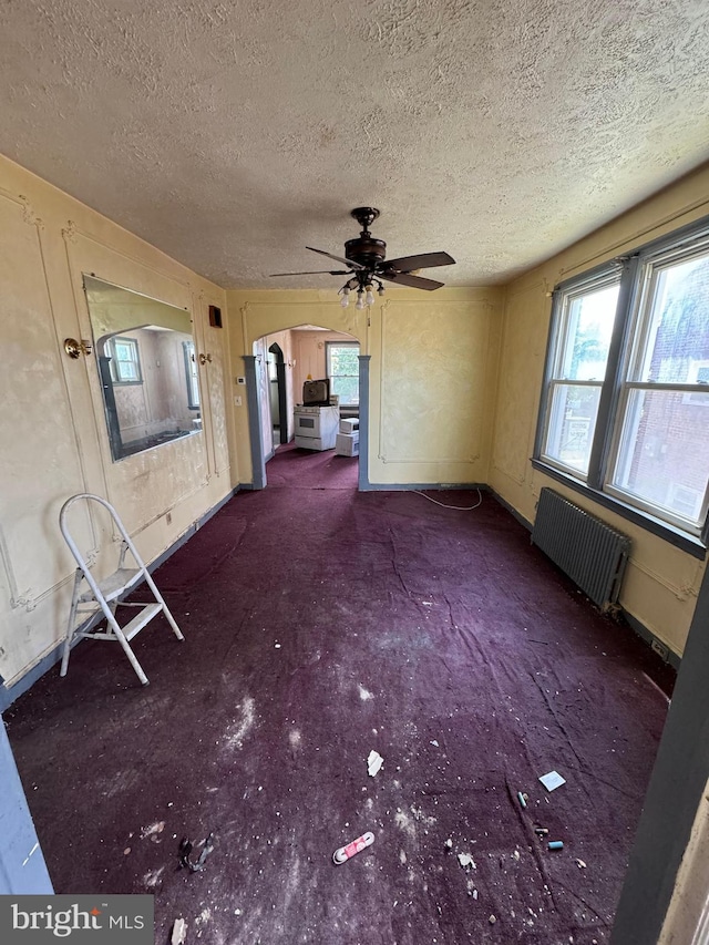 interior space featuring radiator heating unit, a textured ceiling, and ceiling fan