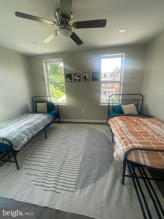 bedroom featuring hardwood / wood-style floors, ceiling fan, and multiple windows