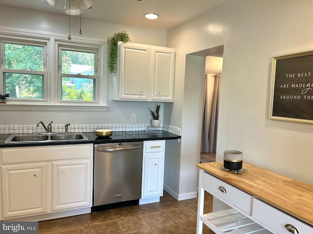 kitchen with stainless steel dishwasher, ceiling fan, white cabinets, sink, and dark tile patterned flooring