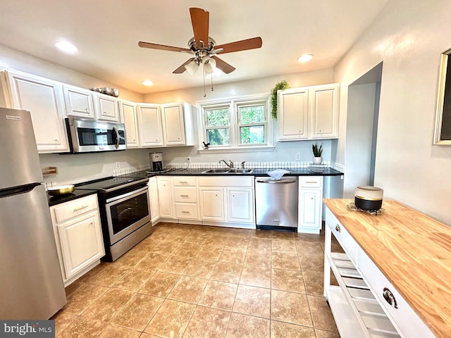 kitchen featuring white cabinetry, light tile patterned floors, ceiling fan, appliances with stainless steel finishes, and sink