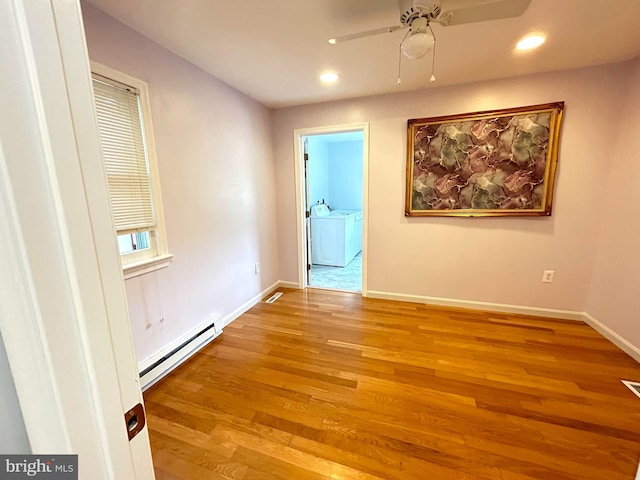 empty room with a baseboard radiator, ceiling fan, light hardwood / wood-style flooring, and washer and clothes dryer