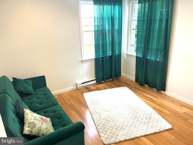 living room with a baseboard radiator, a wealth of natural light, and hardwood / wood-style floors