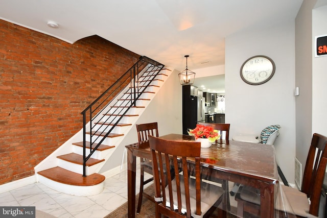 dining space with brick wall and an inviting chandelier