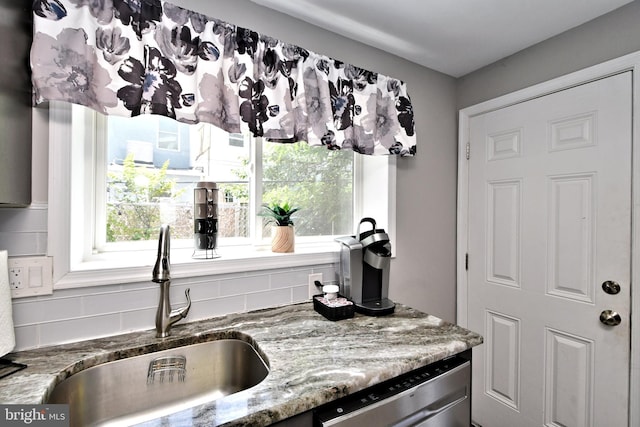 kitchen with stainless steel dishwasher, backsplash, a healthy amount of sunlight, and sink