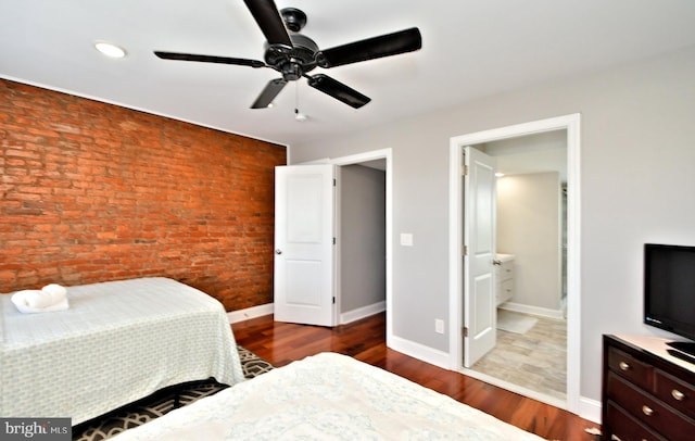 bedroom featuring wood-type flooring, connected bathroom, ceiling fan, and brick wall