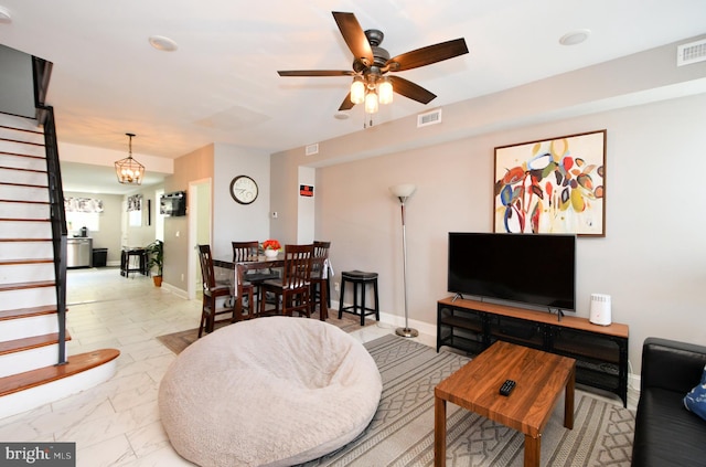 living room with ceiling fan with notable chandelier