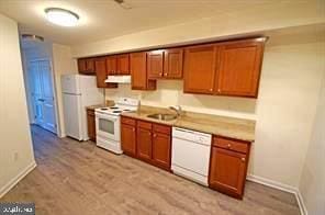 kitchen featuring white appliances, sink, and light hardwood / wood-style flooring