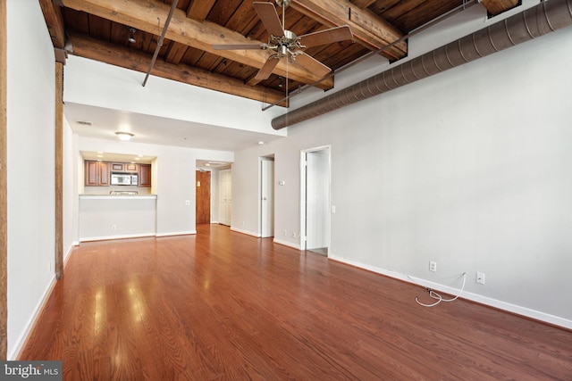 unfurnished living room featuring ceiling fan, beamed ceiling, wood ceiling, and hardwood / wood-style flooring