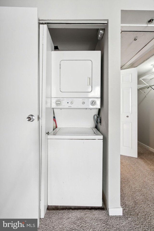 washroom featuring stacked washer / drying machine and light colored carpet