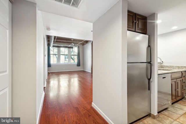 kitchen with light stone countertops, appliances with stainless steel finishes, light hardwood / wood-style floors, and sink