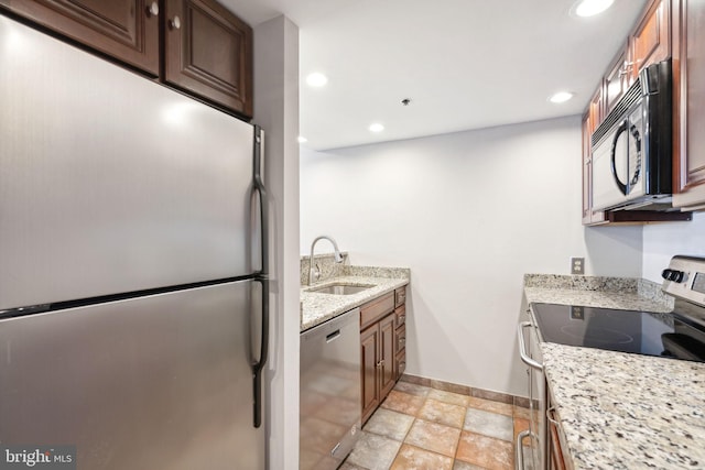 kitchen with light stone countertops, sink, and appliances with stainless steel finishes