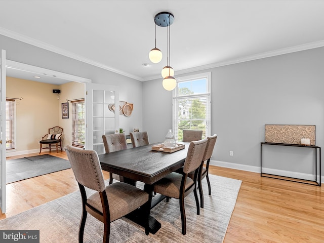 dining space with crown molding and light hardwood / wood-style floors