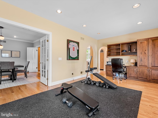 exercise room with light wood-type flooring, ornamental molding, and french doors