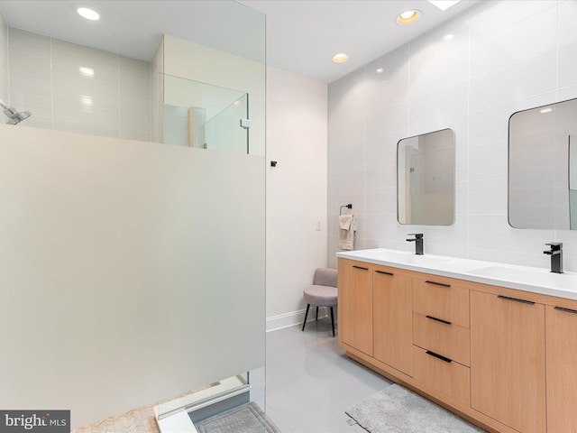 bathroom with tile patterned flooring, a shower, vanity, and tile walls