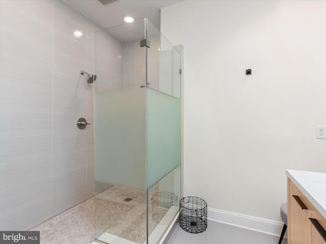 bathroom featuring a tile shower, tile patterned flooring, and vanity