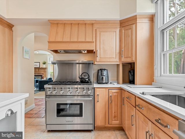 kitchen featuring light tile patterned flooring, light brown cabinetry, high end stainless steel range oven, and custom exhaust hood