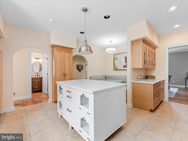 kitchen with decorative light fixtures, a kitchen island, white cabinetry, and light tile patterned floors