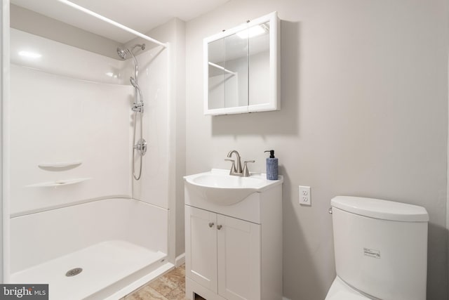 bathroom featuring toilet, vanity, and walk in shower