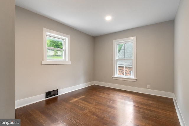 empty room featuring dark hardwood / wood-style flooring and a wealth of natural light