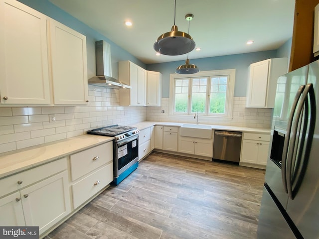 kitchen with white cabinetry, sink, backsplash, stainless steel appliances, and wall chimney exhaust hood