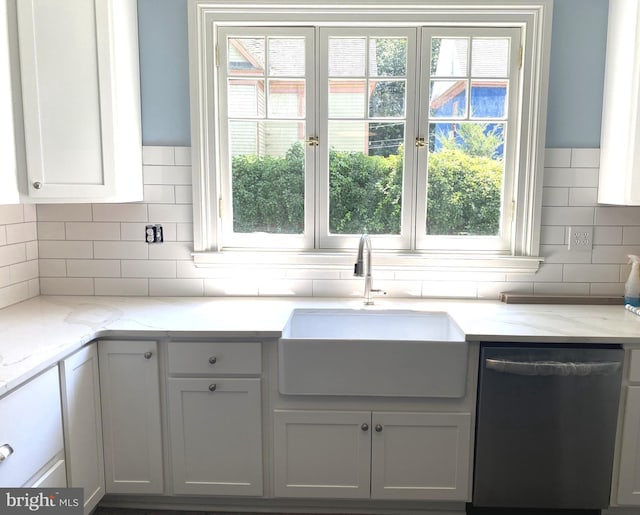 kitchen with sink, dishwasher, white cabinetry, light stone counters, and tasteful backsplash